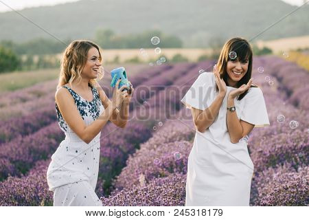 Sister having fun with bubble wand outdoor. Soap bubble fight. 