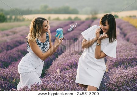 Sister having fun with bubble wand outdoor. Soap bubble fight. 