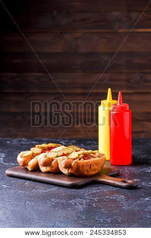 Image Of Hotdogs On Cutting Board At Table With Ketchup And Mustard