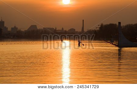 Kayak At Sunset. Canoeing Competition, Sunset And City.
