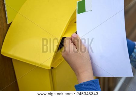 Childs Hand Puts Blank Postcard In An Italian Yellow Post Box Pillar Box