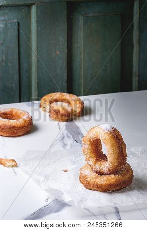 Homemade Puff Pastry Deep Fried Donuts Or Cronuts With Sugar Standing On Crumpled Paper Over White M
