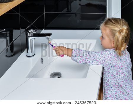 Little Girl Brushing Teeth In The Bathroom