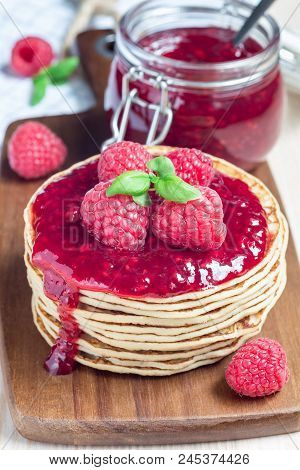 Stack Of Pancakes Or Fritters With Raspberry Jam And Berries On A Wooden Board, Verical