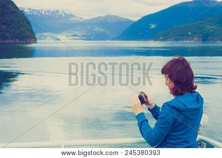 Tourism Vacation And Travel. Tourist Woman On Cruise Ship Enjoying Fjord View, Taking Photo With Cam