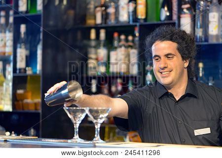 Professional Barman Man Pours A Fresh Cocktail To The Customers Of The Hotel Bar. Focus On The Barte