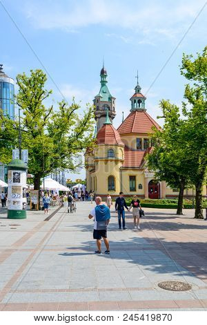 SOPOT - MAY 26: Tourists enjoy the sunny weather and walking in front of the balneological clinic with a lighthouse on 26 May 2018 in Sopot, Poland. The building was built in 1903.