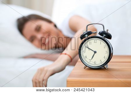 Sleepy Young Woman Stretching Hand To Ringing Alarm Willing Turn It Off. Early Wake Up, Not Getting 