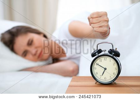 Sleepy Young Woman Stretching Hand To Ringing Alarm Willing Turn It Off. Early Wake Up, Not Getting 