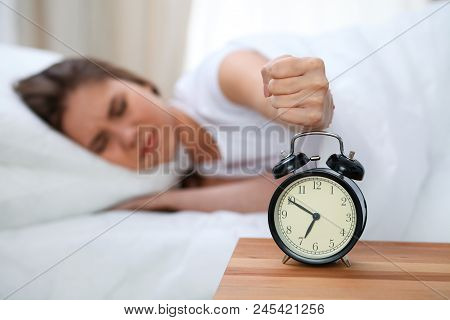 Sleepy Young Woman Stretching Hand To Ringing Alarm Willing Turn It Off. Early Wake Up, Not Getting 