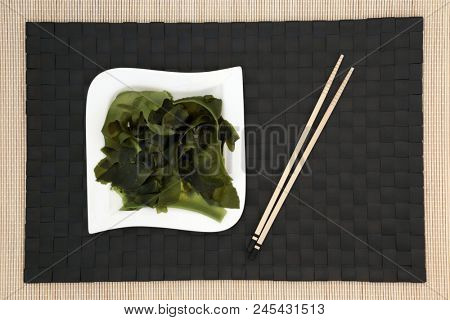 Japanese wakame seaweed green tea with glass teapot and cup, stirrer and whisk on bamboo background. Has many health benefits and is very high in minerals.