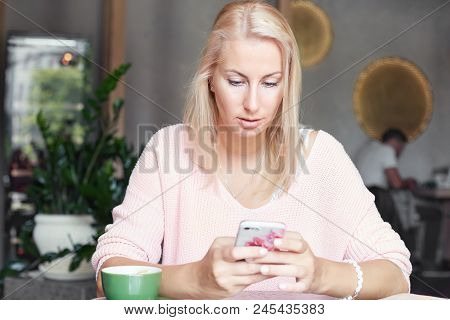 Serious Blond European Female Reads Income Message With Serious Expression, Checks Email Online On S