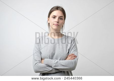 Disappointment, Confusion, Bad Mood. Frustrated Young Woman With Crossed Hands Stands Isolated On Wh