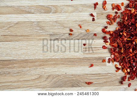 Dried Red Hot Chilly Flakes On Light Wooden Background, Top View, Close-up, Macro, Shallow Depth Of 