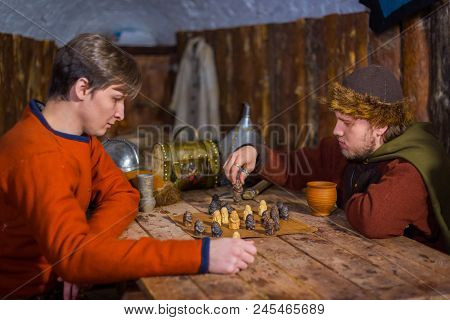 Two Men In Russian Ethnic Suit Playing Medieval Popular Strategy Board Game - Tafl. Folk, Competitio