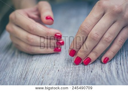Woman Manicured Red Color Nails. Wooden Table Background