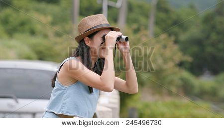 Woman travel with her car and looking though the binocular and enjoy natural landscape 