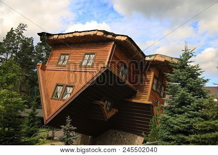 An Upside Down House In Poland Amid Trees.