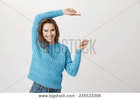 Positive Happy Caucasian Blonde Model Indicating Right With Both Forefingers, Smiling Cheerfully Whi