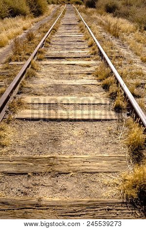 Train Tracks In The Desert With Dry Vegetaion Growing Between The Tracks. A Sunny Day In Jacumba, Ca