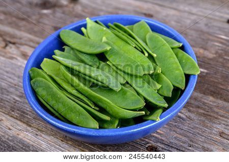 Blue Bowl With Green Peapods  On Wooden Ground