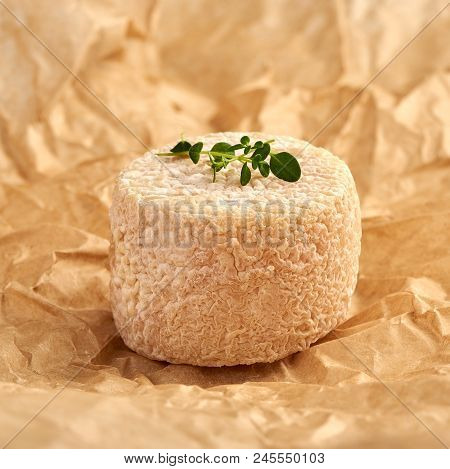 Crottin Cheese With Thyme Leaves On Brown Package Paper.