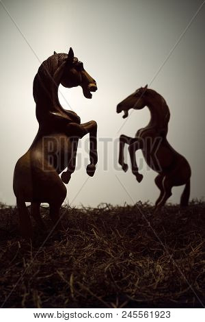 Silhouette A Pair Of Skittish Horse Or Fighting In Grass Filed, The Wood Horse Sculpture Is In Drama