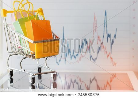 Colourful Paper Bags In Yellow Trolley On Tablet With Chart Background. Consumers Can Buy Products D