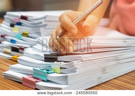Teacher Hand Holds Pen For Checking Student's Homework Assignment On Table Office. Paper Documents S