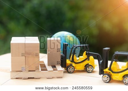 Mini Forklift Trucks Load Stack Of Cardboard Boxes On Wooden Pallet With Nature Background And Globe