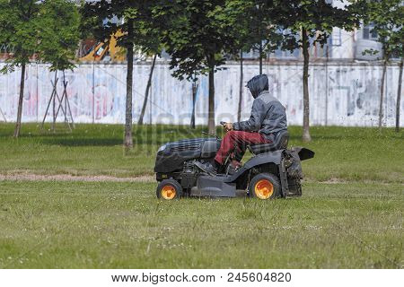 A Man On A Tractor Lawn Mower Mows The Grass