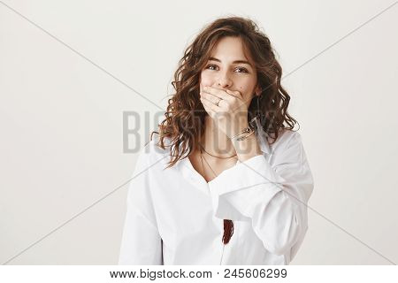 Emotive Charming Caucasian Female Covering Mouth With Hand While Laughing Over Friend, Standing Over