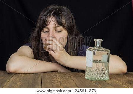 A Girl Drinks Alcohol From A Wine-glass On The Table Is A Bottle With Alcohol, A Black Background