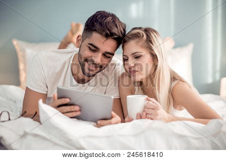 Couple Using  Tablet In Their Bedroom