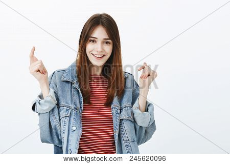Studio Shot Of Ubeat Good-looking Girl With Brown Hair, Raising Hands And Smiling Broadly After Succ