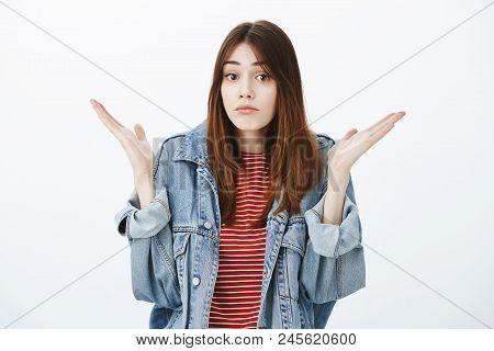 No Clue What Is Happening. Studio Portrait Of Questioned Unaware Attractive Girl With Brown Hair In 