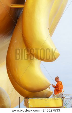Ang Thong/thailand - April 8, 2018: A  Monk Saying Prayer At The Fingers Of Big Golden Buddha Image 