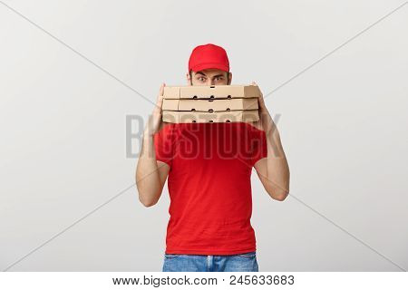 A Deliveryman Hidden Behind A Large Stack Of Pizza Boxes He Is Carrying. Isolated Over Grey Backgrou