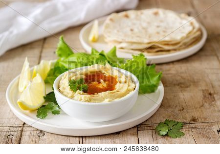 Hummus With Olive Oil And Paprika, Served With Pita, Lemon And Lettuce Leaves. Selective Focus.