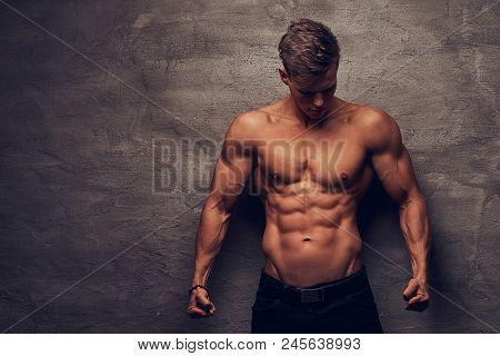Beautiful Shirtless Young Man Model With Nice Muscular Body Posing At A Studio. Isolated On A Dark B