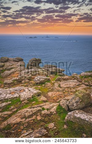Large Boulders On The Coast And Small Lighthouse On The Background In The Lands End - The Most Weste