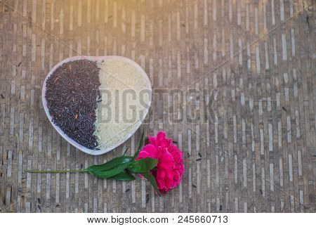 On Seletive Focus Of  Heart-shaped Cup That Put Rice Berry & Flowers Pink.