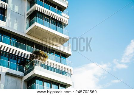 The Corner Of The Building With Many Windows Against The Blue Sky.