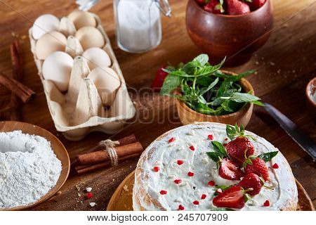 Top View Raw Ingredients For Cooking Strawberry Pie Or Cake On Wooden Table: Eggs, Sugar, Mint And S
