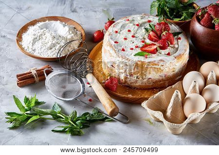 Strawberry Tart Covered With Whipped Sour Cream Surrounded By Organic Ingredients Over White Backgro
