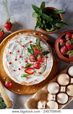Strawberry Tart Covered With Whipped Sour Cream Surrounded By Organic Ingredients Over White Backgro