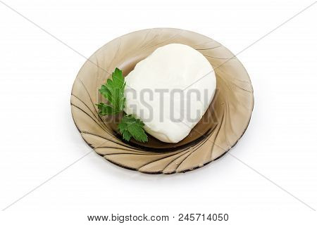 Piece Of The Mozzarella Cheese With Leaves Of Parsley On The Dark Glass Saucer On A White Background