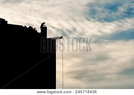 The Builder At The Construction Site Works At Sunset, At Dawn