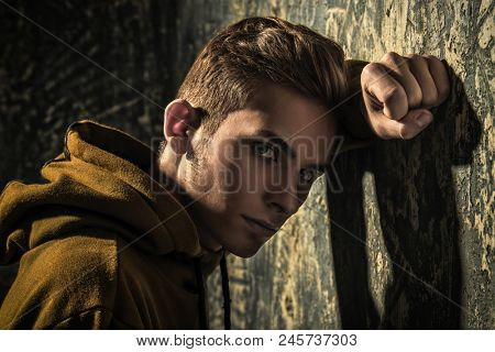 Portrait of a sad teenage boy over grunge background. Studio shot. Teen fashion.