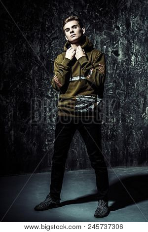 Portrait of a teenage boy over grunge background. Full length portrait. Studio shot. Teen fashion.